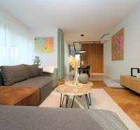 A stylish living room in a 4-room apartment with a wood-patterned floor and artistic paintings.