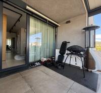 Balcony of a 4-room apartment with a grill, chair, and view of Dúbravka.