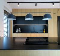 A kitchen in a 4-room apartment with black and wooden elements, pendant lighting.