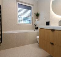 A bathroom in a 4-room apartment with a bathtub, sink, and wooden cabinet decor.