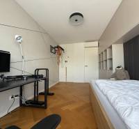 A room in a 4-room apartment with a bed, a table, and a floor with a wooden decor.