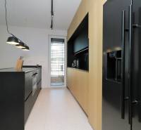 A kitchen in a 4-room apartment with a black countertop and wooden cabinets.