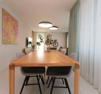 Dining room with a large wooden table, chairs, and curtains in a 4-room apartment.