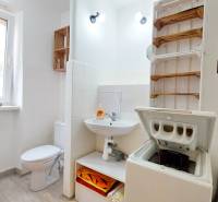 A bathroom in a 2-room apartment with a washing machine, a sanitizer, and a towel rack.