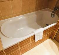 A bathroom in a studio apartment with a bathtub and ochre tiles.