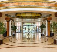 Hotel lobby with marble flooring, high ceiling, and decorative lighting.