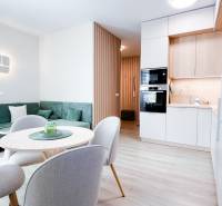 Living room and kitchen in a 3-room apartment with a wooden decor floor and a green sofa.
