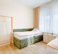Bright room with a bed and wood-decorated flooring in a 3-room apartment.