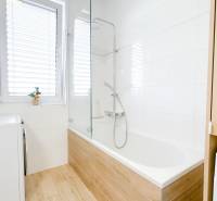 Bathroom in a 3-room apartment with a bathtub and a floor with a wooden decor.