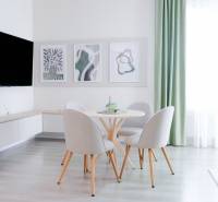 Dining area in a 3-room apartment with decorative paintings and a large window.