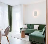 3-room apartment with a green sofa, curtains, and a floor with a wooden decor.