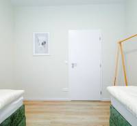 A bright bedroom in a 3-room apartment with a wood-patterned floor and minimalist decor.