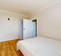 A room in a one-room apartment with a wooden decor floor and simple furniture.