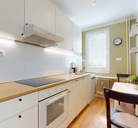 A kitchen in a studio apartment with white cabinets and a wood-patterned floor.