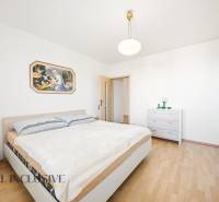 Bedroom with wood-patterned flooring in a family house and a painting on the wall.