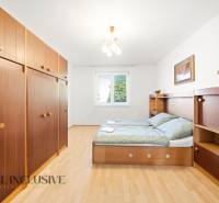 Bedroom in a family house with wood-patterned flooring, storage space, and a bed.