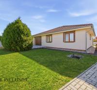 A family house in Kútniky with a lawn, trees, and paving.