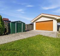 A garage with a wooden gate in a family house in Kútniky, with a lawn and a walkway.
