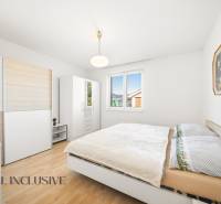 A bedroom in a family house with a wooden decor floor, white furniture, and a painting.