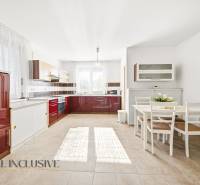 A bright kitchen in a family house with red cabinets and a dining table.