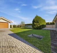 A family house in Kútniky with a garage, lawn, and paved access road.