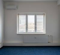 A room with air conditioning and a window in the offices, blue carpet, white walls.