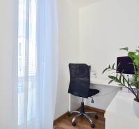 A workspace with a computer, a black chair, and a plant on a floor with a wooden decor.