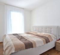 Bedroom with a bed and a nightstand in a three-room apartment, floor with wooden decor.