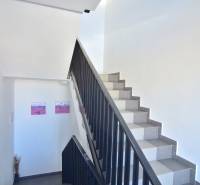 A staircase with white walls and decorations in a three-room apartment.
