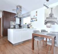 A kitchen in a 3-room apartment with a wooden decor floor and a dining table.