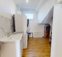 Laundry room with wood-patterned flooring, washing machine, dryer, and sink in a family house.