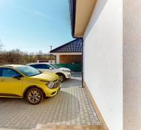 A yellow car parked by a family house in Horné Štitáre, sunny day, paving.