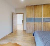 Bedroom with a sliding wardrobe and a wooden decor floor in a family house.