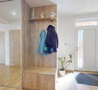 Interior of a family house with a wooden decor floor and a mirrored wardrobe by the door.