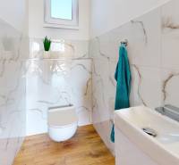 A bathroom in a family house with a wooden decor floor and marble wall tiles.