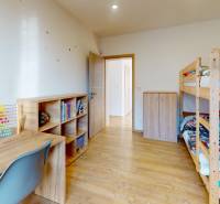 Children's room in a family house with a wooden decor floor, a bunk bed, and a desk.