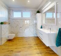 A bathroom in a family house with a wooden decor floor and marble-look tiles.