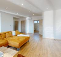 Living room in a family house with a wood-patterned floor and a yellow sofa.