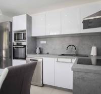 A kitchen in a 2-room apartment with stainless steel appliances and a gray countertop.