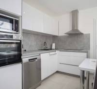 A kitchen in a 2-room apartment with built-in appliances and a dining area.