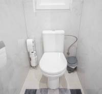 Bathroom with toilet in a 2-room apartment, light tiles and accessories in neutral colors.