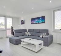 A bright living room with a sofa and wood-patterned flooring in a two-room apartment.