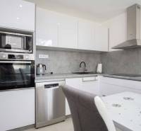 Kitchen area of a 2-room apartment with white cabinets and a gray countertop.