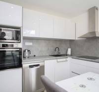 A modern kitchen with white cabinets in a 2-room apartment, equipped with appliances and a range hood.