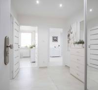 A bright entrance hallway in a 2-room apartment with modern decor and hanging paintings.