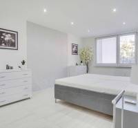 A bright bedroom in a two-room apartment with white furniture and decorations.
