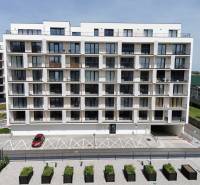 A modern apartment building with parking spaces and greenery on Eduarda Wenzla Street in Bratislava - Rača.