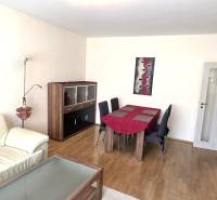 Living room with a sofa, dining table, and floor with wood decor in a 3-room apartment.