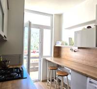 A kitchen in a 3-room apartment with a bar counter, microwave, and cooktop.