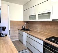 A kitchen in a 3-room apartment with a wooden decor countertop and floor.